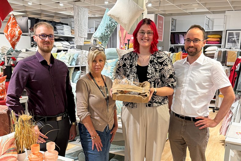 Bild mit 4 Personen, die Auszubildende hat ein Geschenk überreicht bekommen von der Geschäftsführung und Ihren Ausbildern