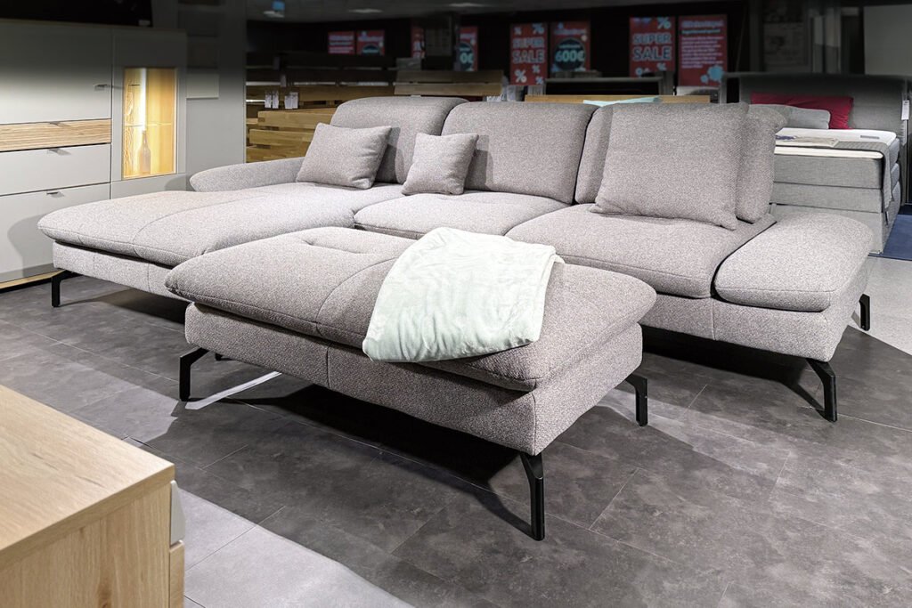 Eckkombination Bezug Stoff grau mit passendem Hocker grau und drei grauen Kissen