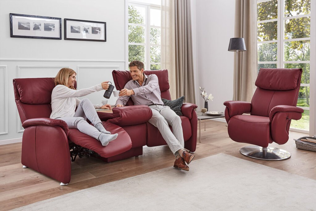 Trapezsofa mit Bezug in Leder Rot, inklusive Relaxfunktion und Schmetterlingstisch. Passender Sessel daneben