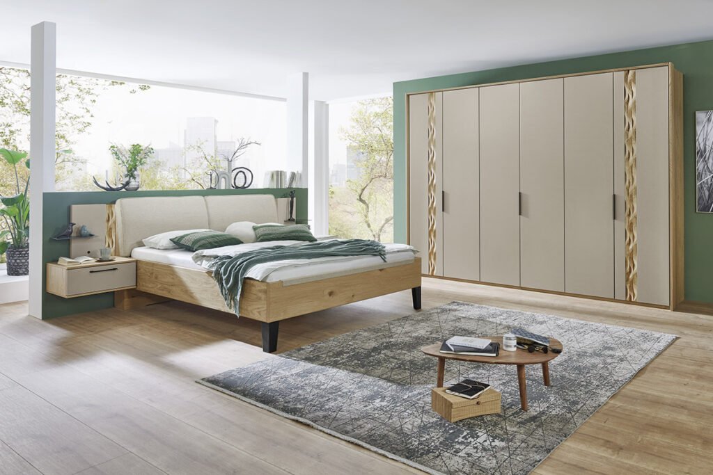 Schlafzimmer Balkeneiche Lack Raupe, bestehend aus sechs türigen Kleiderschrank, Außentüren mit Wellenprofil, inklusive Passepartout, Bettanlage mit Polsterkopfteil, Stoff Senta Beige, zwei Hängenachtkonsolen, inklusive Paneelaufsätzen mit Glasböden und Wellenprofil