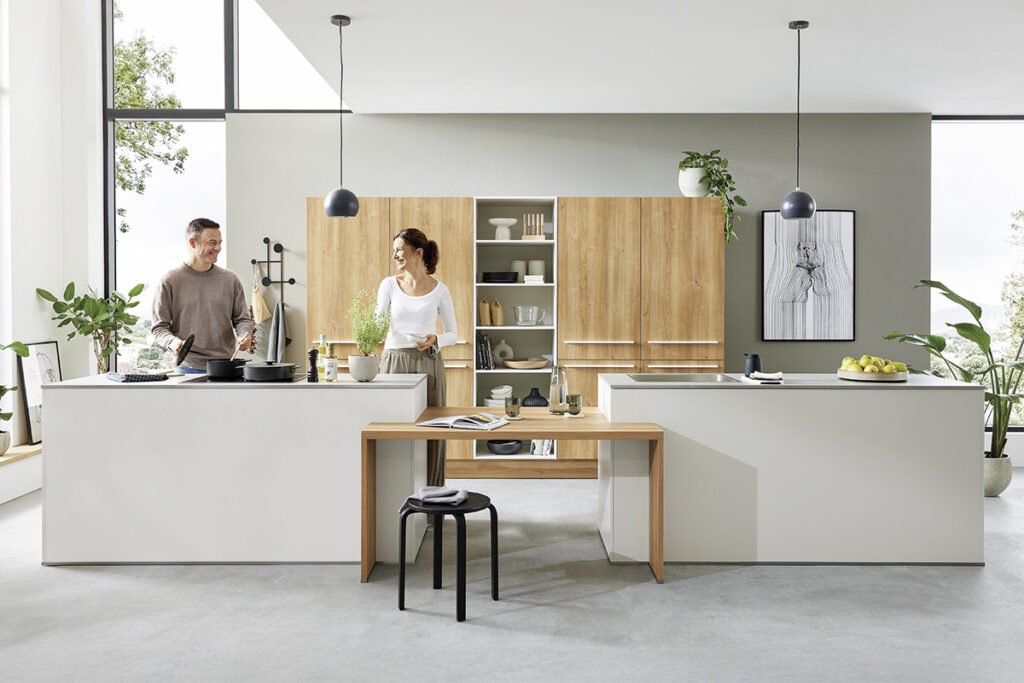 Front-Kombi aus Lacklaminat Muschelweiß matt und Aurora Eiche Nachbildung, Arbeitsplatten Beton Quarzgrau Nachbildung, bestehend aus Hochschrankelement mit 2 Inseln und Verbindungstisch. Mit hochwertigen Elektrogeräten von Constructa und Einbauspüle, ohne Deko