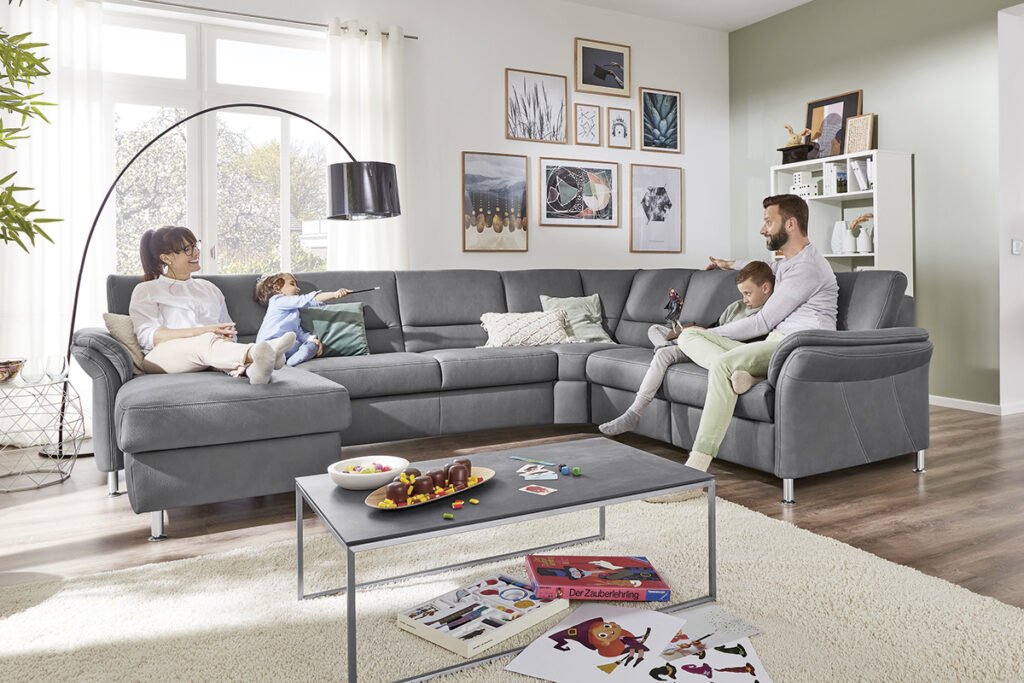 Wohnlandschaft Grau auf der eine Familie sitzt