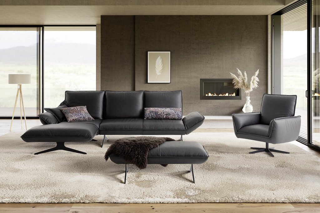 Ecksofa mit Lederbezug in Schwarz und Metallkufen, dazu ein passender Hocker und Sessel