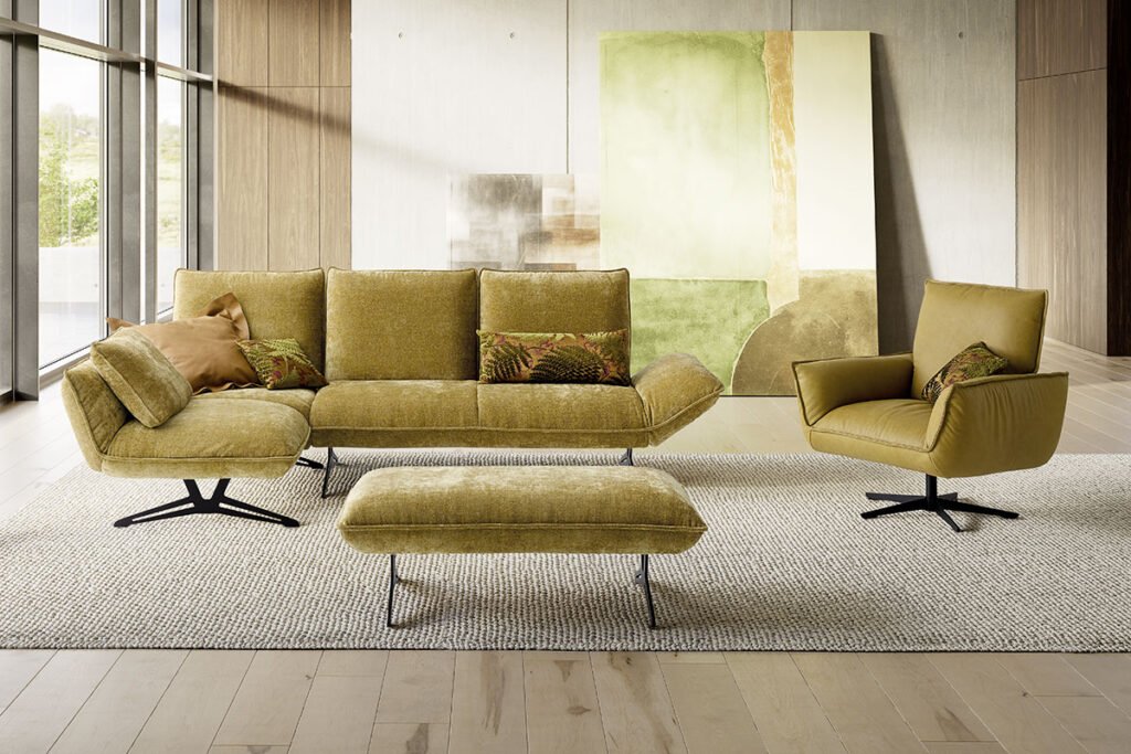 Ecksofa mit Stoffbezug in Gelb/Grün und Metallkufen, dazu ein Hocker und ein Sessel