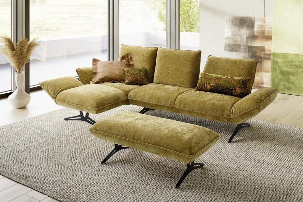 Ecksofa mit Stoffbezug in Gelb/Grün und Metallkufen, dazu ein Hocker